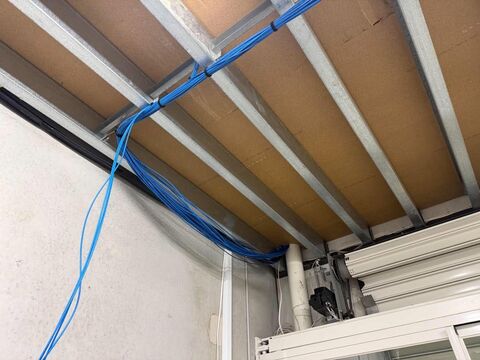 Blue data cables run neatly along the ceiling framing